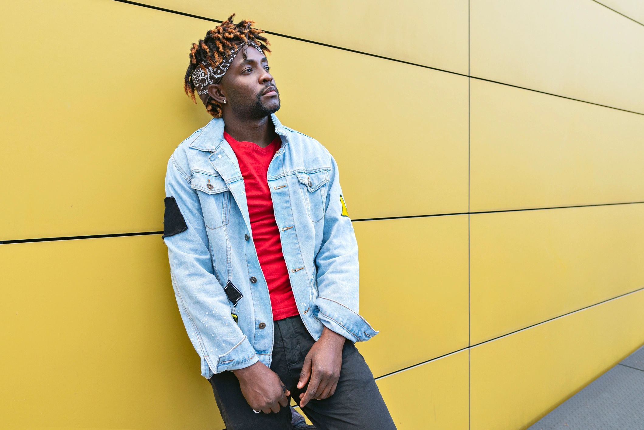 Artist portrait leaning against a bright yellow wall